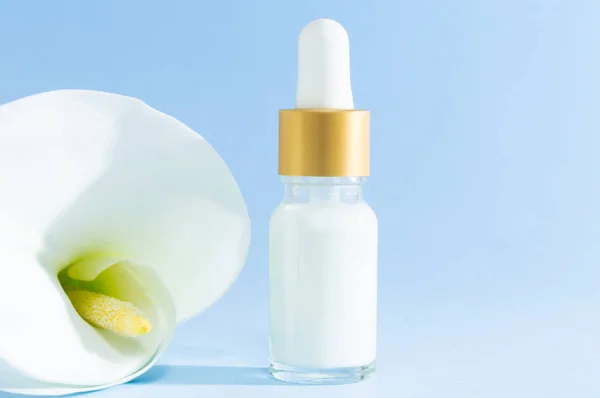 Naturkosmetik: serum med pipett och Calla Lily Flower på blå bakgrund. — Stockfoto