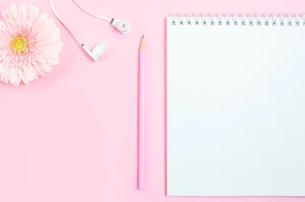 Χώρος εργασίας: σημειωματάριο, μολύβι, ακουστικά και άνθη ζέρμπερας σε ροζ φόντο. Minimalism, flat-lay, top view, αντιγραφή χώρου. — Φωτογραφία Αρχείου