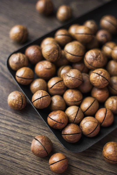 ahşap masa üzerinde bir sqare plaka içinde macadamia fındık
