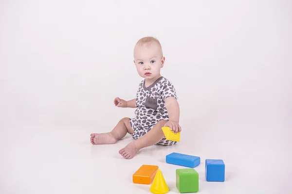little child plays in cubes on white background