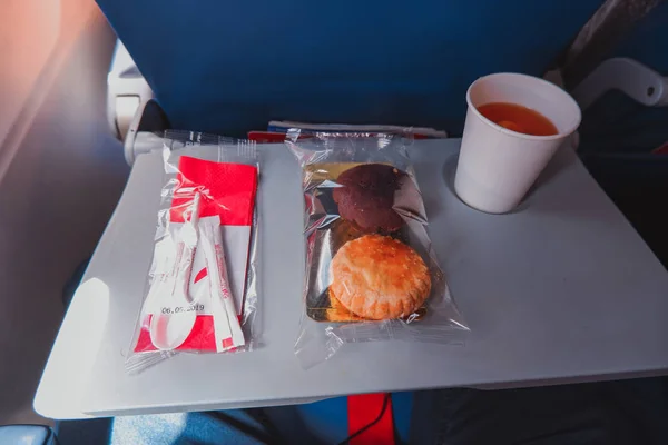 Saint-Petersburg / Russia - June 18 2019: Airline meal in flight from Rossiya Airlines. Cup of tea, cake and buscuit. — Stock Photo, Image