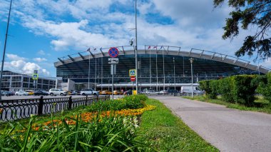 Moskova / Rusya - 18 Haziran 2019: Vnokovo Havaalanı'na çiçeklerle dolu yeşil sokak. Arka planda terminal yakınında taksi ve arabalar.