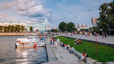 Yekaterinburg / Rusya - 10 Ağustos 2019: İnsanlar Yekaterinburg'un merkezindeki Iset nehri üzerinde yürüyor. Arka planda Dom N.i. Sevastyanova, Lenina sokak ve Antey kulesi