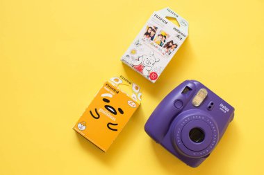 Fujifilm instax mini camera and gudetama and Winnie the Pooh instant film on yellow background clipart