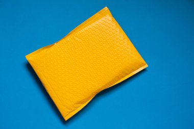 Sarı zarf bubble Wrap için yapılan bir şey darbeleme veya mavi zemin üzerine darbeye dayanıklı önlemek