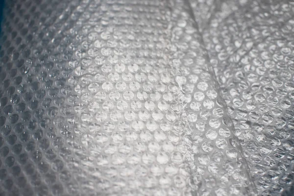 Bubble wrap on blue background. Bubble wrap is a pliable transparent plastic material used for packing fragile items.