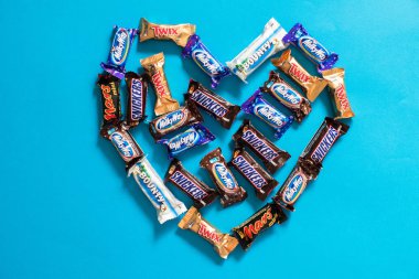 Twix, Samanyolu, Snickers, ödül, Mars popüler mini şeker çikolata üzerinde arka planda mavi kalp şekli