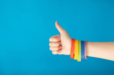 Gökkuşağı bayrağı Lgbt bileklik bilezik mavi zemin üzerine el üzerinde. Eşcinsel gurur kavramı. Homoseksüel aşk için oy.