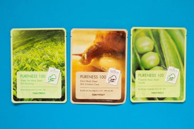 Tony Moly levha maskeleri düz mavi arka plan üzerinde yatıyordu. Kore Kozmetik üst görünümü.