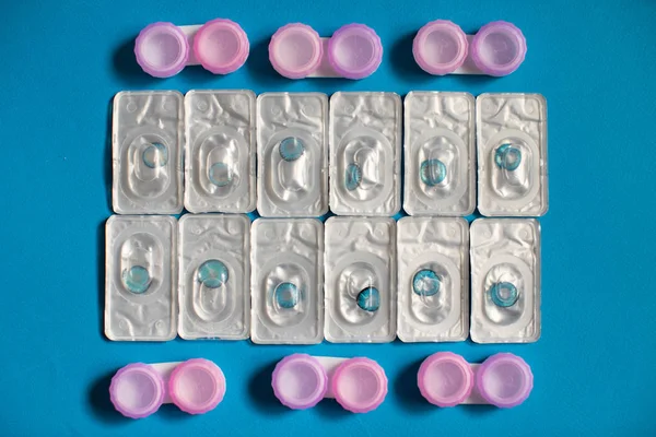 Color contact lenses in blisters and contact lens cases on blue background