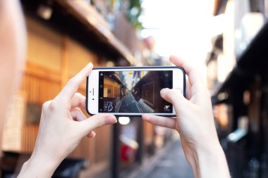 Kyoto 'nun Iphone, Instagram blogger konsepti, Japonya yakınlarındaki küçük sakin caddesinin fotoğrafını çeken kız.