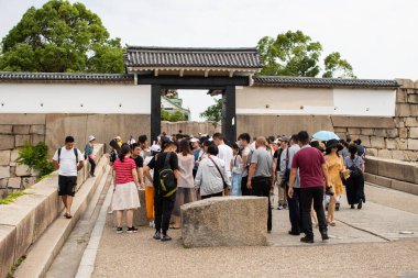 İnsanlar Osaka Kalesi 'ne yürür. Osaka Kalesi Parkı' ndan geçer. Bir sürü turist, Japonya. Şato Japonya 'nın en ünlü simgelerinden biridir ve Azuchi-Momoyama döneminde Japonya' nın birleşmesinde önemli bir rol oynamıştır..
