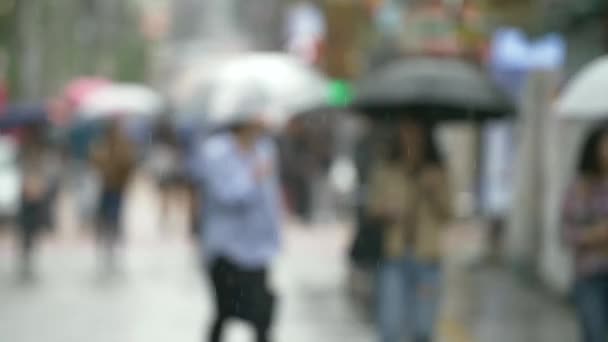 An out of focus shot of people walking in the rain — Stock Video