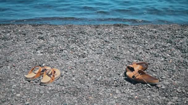 Twee paar sandalen op een strand in Griekenland — Stockvideo