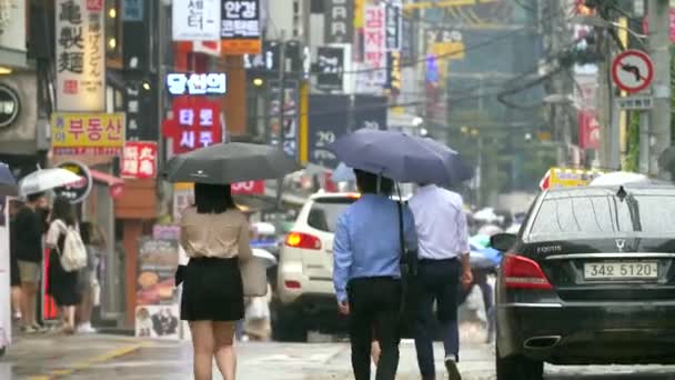 Menschen, die eine nasse Straße in Seoul hinuntergehen — Stockvideo