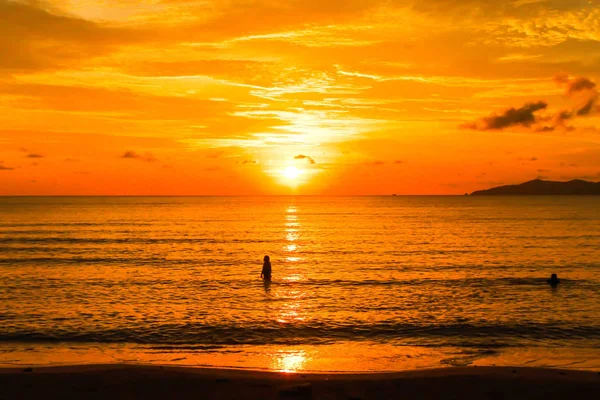 オレンジ色の海の夕日とタイのシルエットの人々の眺め ストック写真