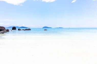 Deniz manzaralı, büyük karanlık taş ve Tayland mavi gökyüzü ile beyaz kum