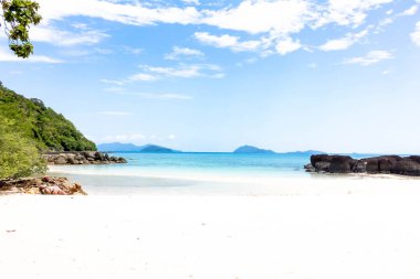 Ada, büyük karanlık taş ve Tayland mavi gökyüzü ile beyaz kum manzara