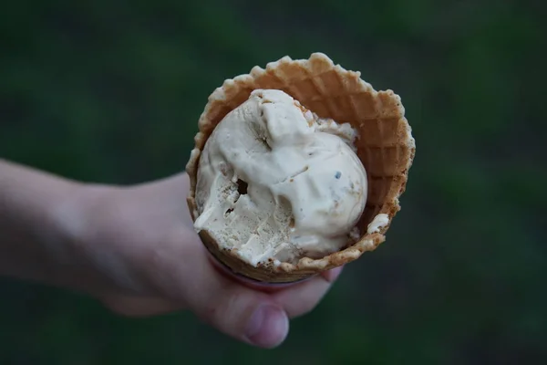 アイスクリームボールはウエハカップで剥がされ 上からぼやけた背景に子供の手を保持します — ストック写真