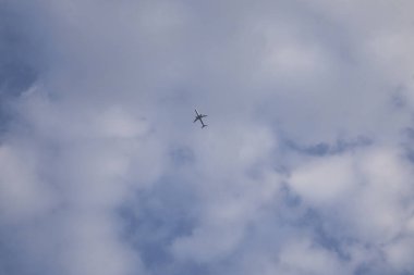 Uçak mavi gökyüzünde yüksekte ve yerin dibinden bulutlar var.