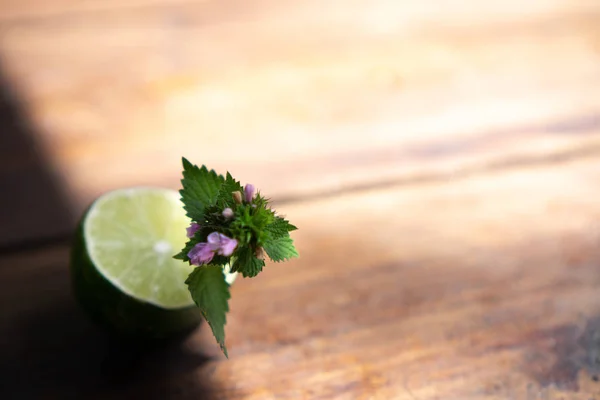 Lime with a sprig of flowers with flowers on an old brown tree table. Blurry background