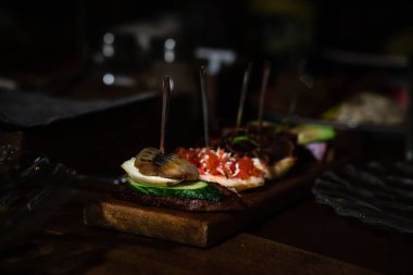 Farklı doldurma ile şiş ler üzerinde Sandviçler. Salatalık ve ringa balığı, domates, beyaz peynir. Tahta bir tahtada servis edilir. Yatay yönlendirme.