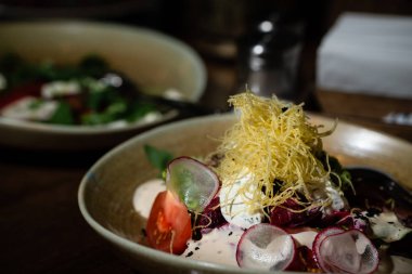 Beyaz turp ve domates salatası ön planda üstüne ince makarna ile. Bulanık arka plan. Catering. Koyu ton. Yatay yönlendirme.