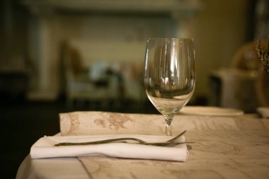 Boş bardak, katlanmış beyaz peçete ve çatal. Restoran servisi. Arka plan bulanık. Sıcak bir ton. Yatay yönelim.