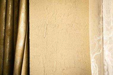 Açık sarı desenli duvar, koyu perde ve beyaz tül. Sıcak bir ton. Yatay yönelim.