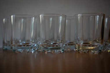 Ahşap bir yüzey üzerinde camdan yapılmış bir grup ayakta duruyor. Bardaklar boş, temiz. Yatay yönelim.