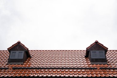 Bulutlu gri sonbahar yağmurlu gökyüzünün arka planında terracotta fayansları olan çatı. Sonbahar havası. Soğuk tonda. Yağmurlu bir gün. Yatay yönelim.