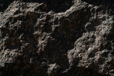 Taş duvar arka planı koyu. Duvarda büyük taş bloklar var. Karanlık bir duvarda gölgeler ve ışıklar oyunu.
