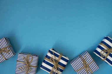 Düz mavi bir yüzey üzerinde el işi halatla çizgili bir dekoru olan hediye kutuları.