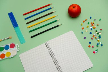 Not defteri, kalem, cetvel ve elma ile yeşil bir yüzey üzerinde cetvel ve cetvelle çalışma öğeleri