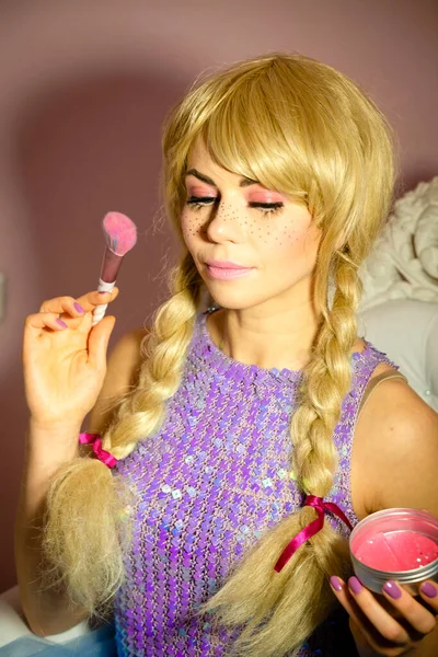 Makeup with blushes for a beautiful woman in a doll costume with a wig for a themed party