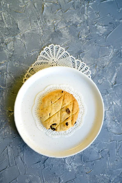 Kuru üzümlü yuvarlak kurabiyeler gri arka planda beyaz yuvarlak bir tabakta