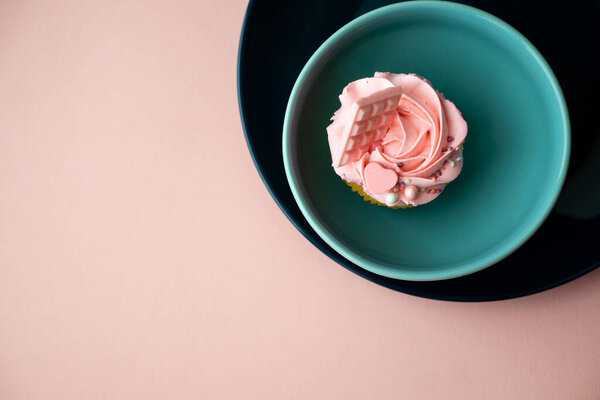 Круглая форма голубых тарелок и розового теста со сливочным кремом на розовой поверхности. Кекс в подарок на праздник или девичник.