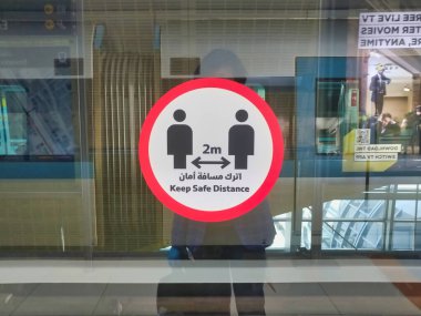 Dubai, Birleşik Arap Emirlikleri - 2 Nisan 2020: Dubai Metro İstasyonunda farkındalık etiketleri, Arap araçları: COVID-19 'un yayılmasına engel olmak için güvenli mesafeyi koruyun