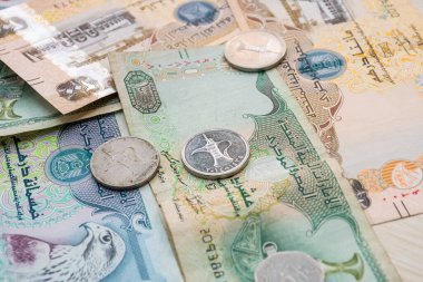 Farklı BAE dirhams döviz notları ve bozuk paralar, yüksek açılı beyaz bir masa üzerindeki kağıt para