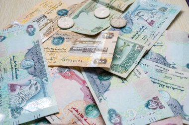Farklı BAE dirhams döviz notları ve bozuk paralar, yüksek açılı beyaz bir masa üzerindeki kağıt para