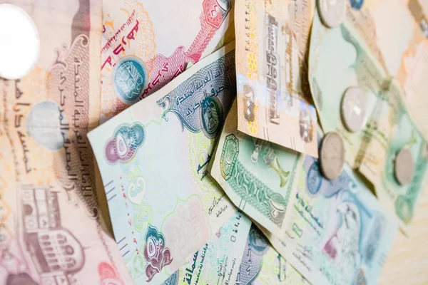 Farklı BAE dirhams döviz notları ve bozuk paralar, yüksek açılı beyaz bir masa üzerindeki kağıt para