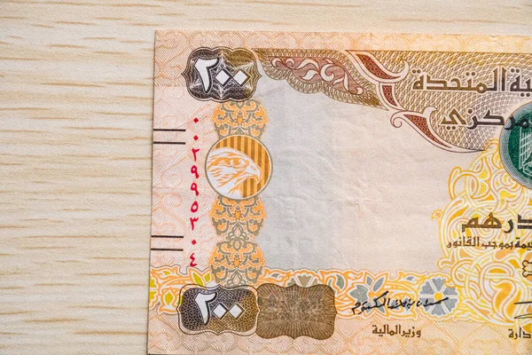 BAE 200 dirhem para birimi notlarını yüksek açılı ve kağıt paralı hafif ahşap masaya yakın çekim