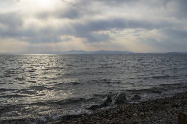 Bulutların arasından denize parlayan güneş ışığı milleri.  