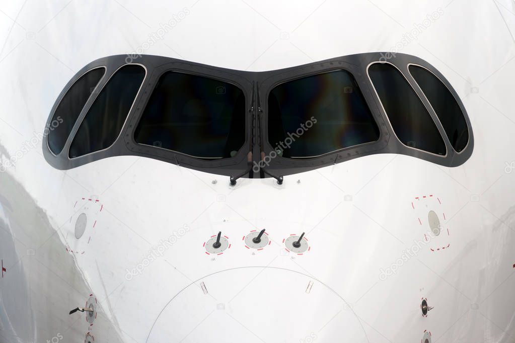Close front outside view of a white big jet plane cockpit.