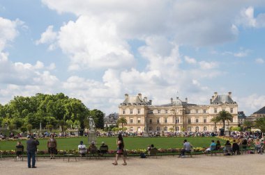 Paris - 13 Temmuz 2014: Bulutlu bir yaz gününde turistlerle dolu Lüksemburg bahçelerinin ve sarayının yatay görünümü