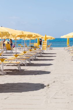 Güneşli bir yaz gününde Lido Di Ostia'daki plaj olanaklarının keyfini çıkaran plaj şemsiyelerinin ve turistlerin dikey görünümü. Bu güzel plaj Roma'ya sadece 30 km uzaklıktadır.