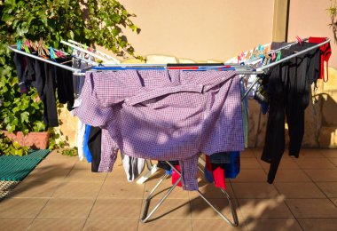 güneşli bir günde bir bahçe satırında yıkama tutan birçok farklı kıyafetler