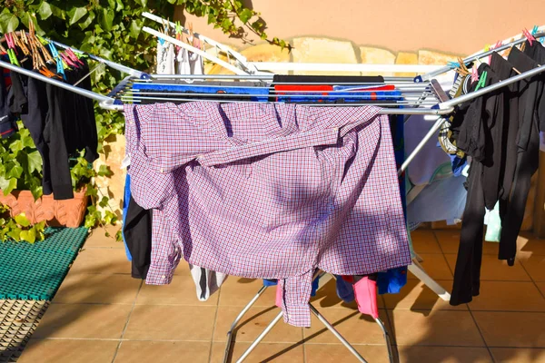 Muchas prendas diferentes que sostienen en la línea de lavado en un jardín en un día soleado — Foto de Stock