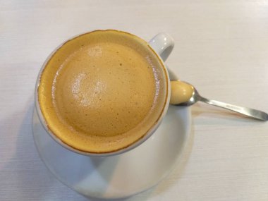 Beyaz fincan kahve süt beyaz bir tablo üzerinde beyaz bir daire üzerinde metalik bir çay kaşığı ile