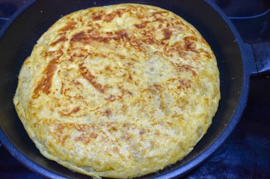 lezzetli İspanyol omleti bir indüksiyon Ocak üzerinde siyah bir tavada pişmiş yumurta, patates, soğan ile